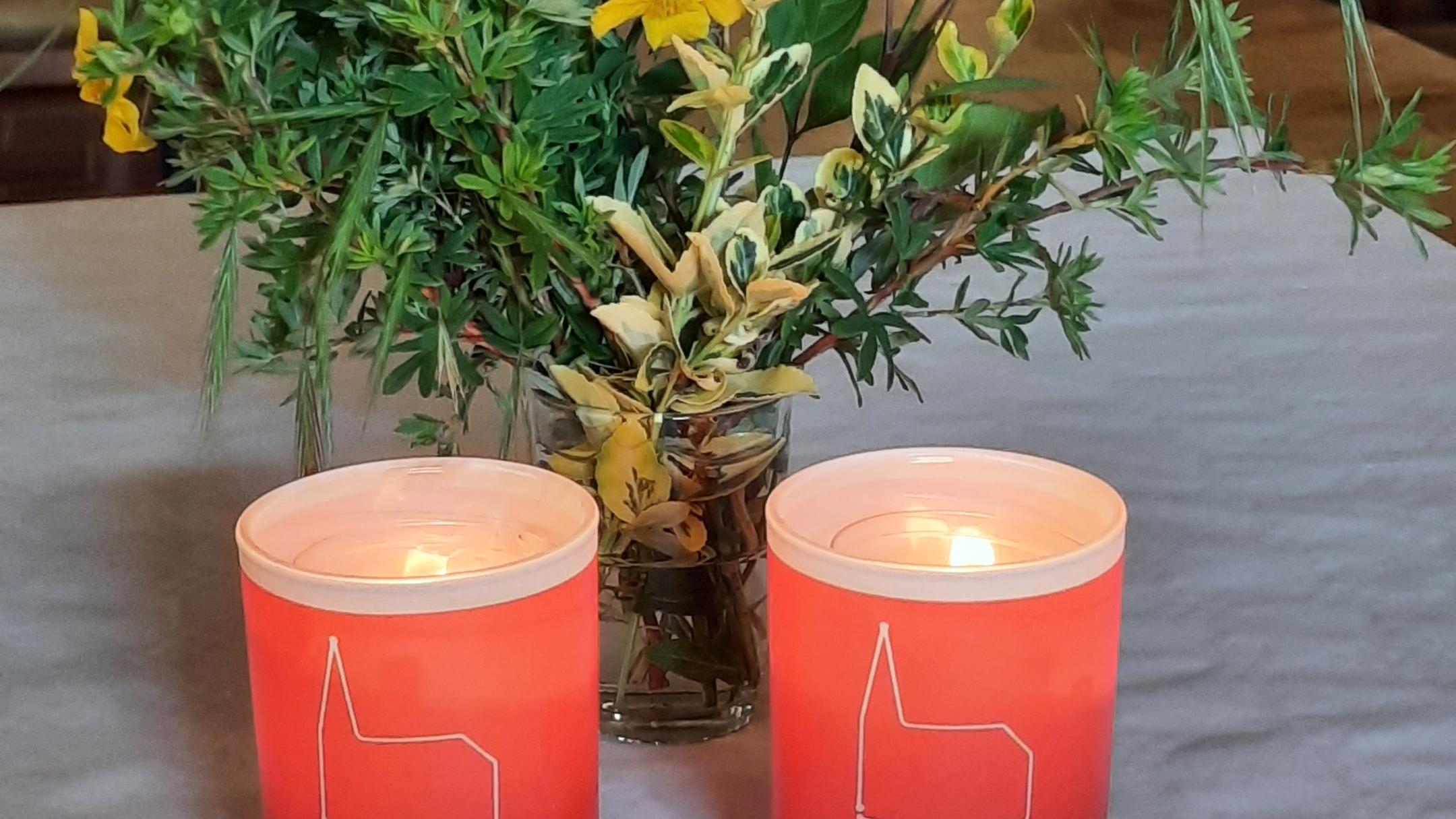 zwei Kerzen der Nacht der offenen Kirche brennen vor grünen Zweigen