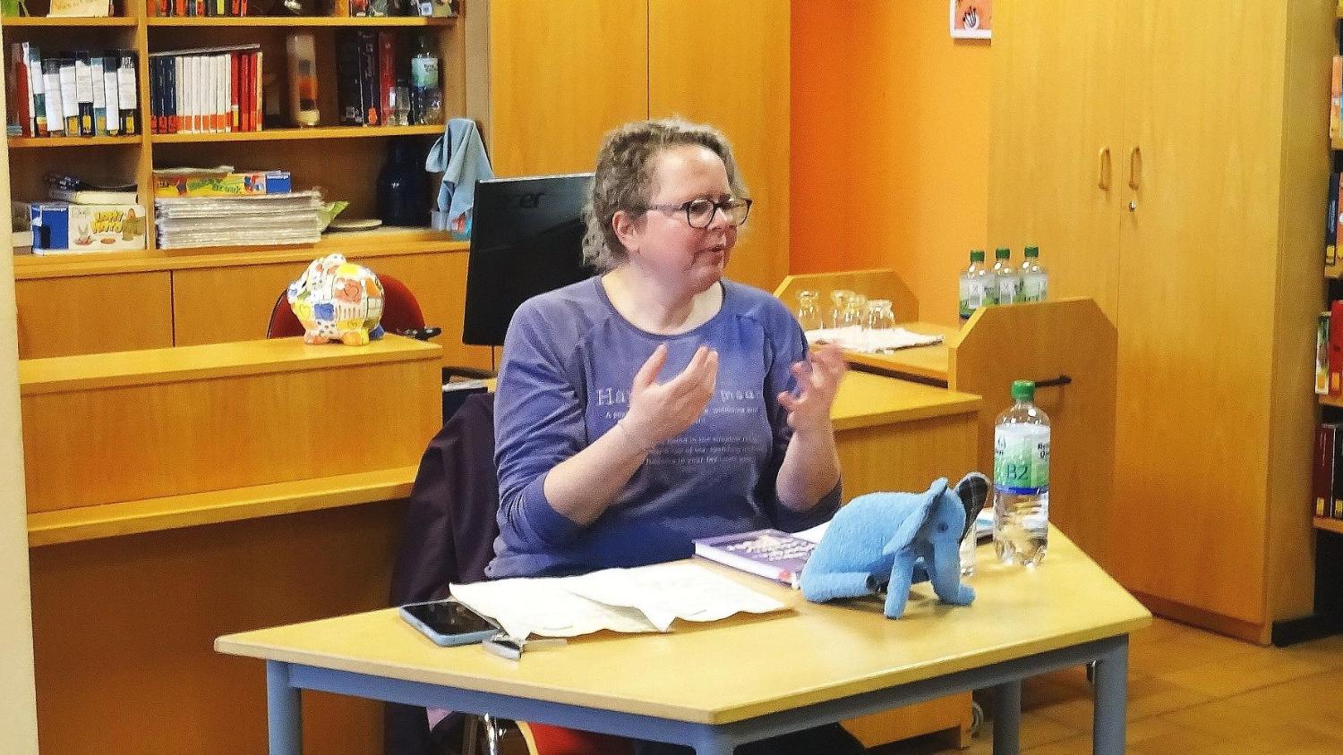 Eine Dame sitzt an einem Tisch und erzählt