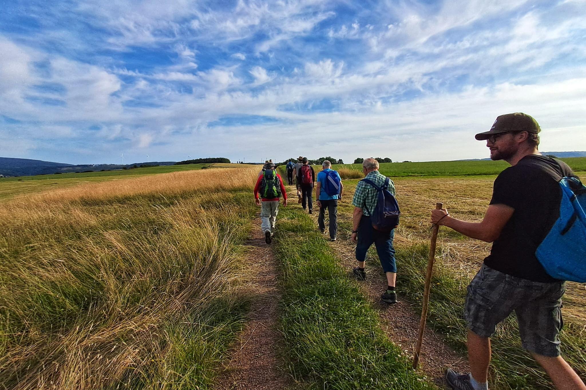 Männer wandern über eine grüne Wiese