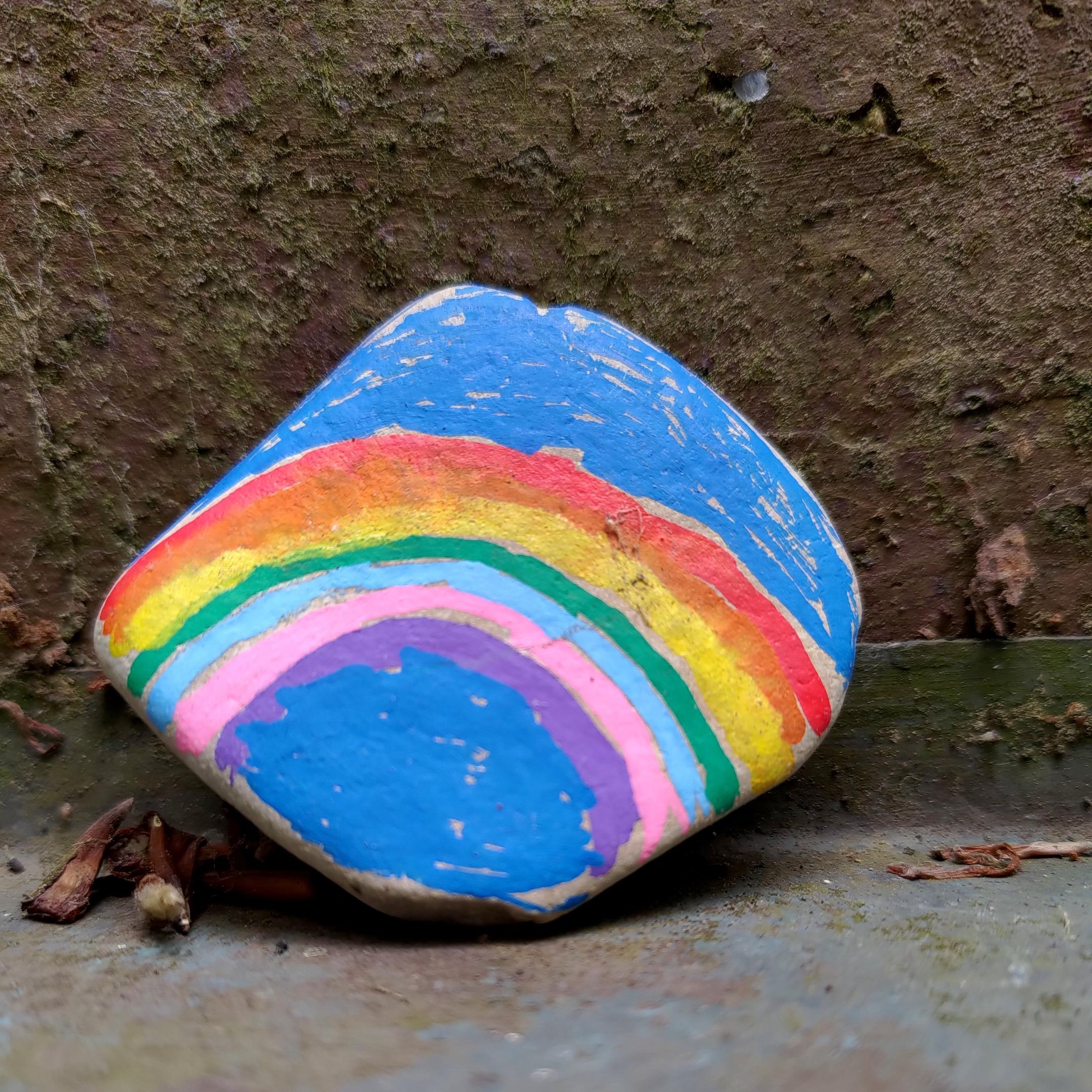 Ein Stein mit einem Regenbogen gemalt