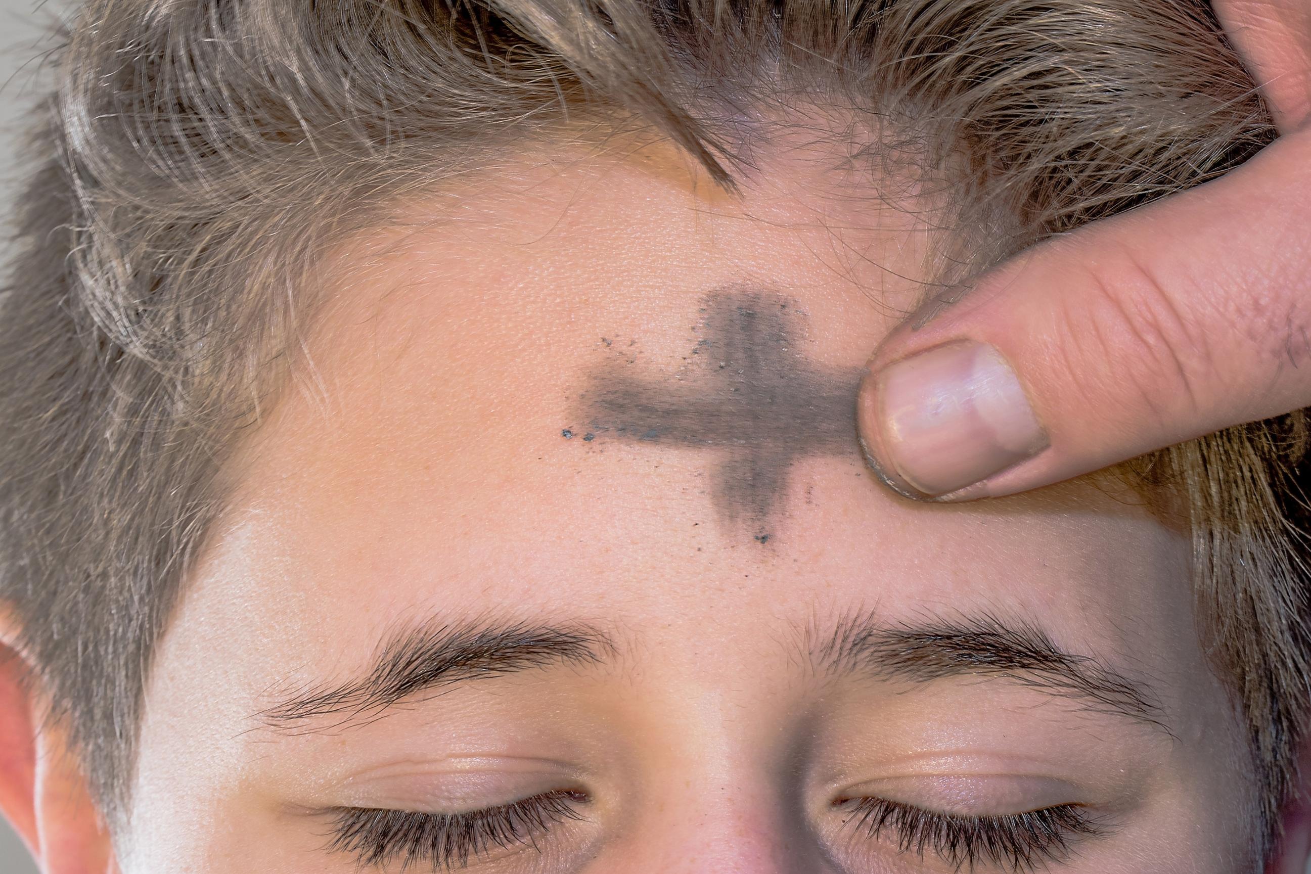 Auf die Stirn eines Kindes wird ein Aschenkreuz geszeichnet